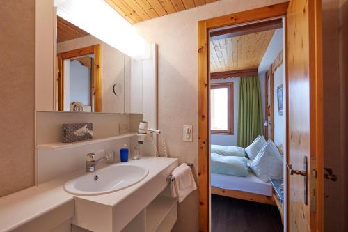 贝特默阿尔卑Hotel Waldhaus的一间带水槽和镜子的浴室以及一张床