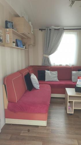 滨海圣佩Sylvie propriétaire du mobil-home " Camping de la Chanterie"的客厅里的一个红色沙发,带有窗户