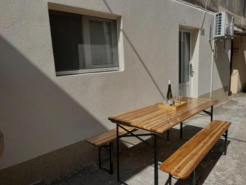 斯塔里格勒Secret Place Apartment的一张木桌,配有一瓶葡萄酒和两把长椅