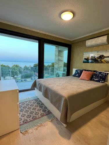 下厄尔什Club Panorama Lake View Apartment的一间卧室设有一张床和一个大窗户