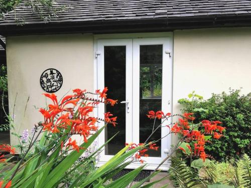 巴顿尼德伍的Canalside Cottage的白色房子的前门,有红色的花