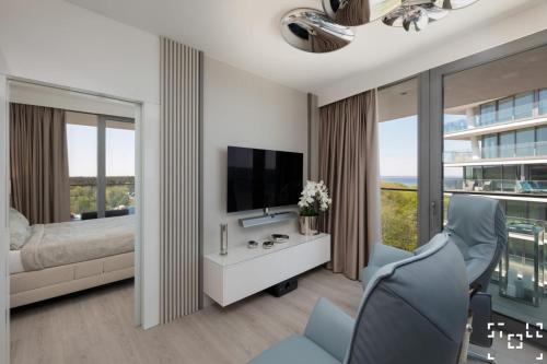 米兹多洛杰Wave Międzyzdroje - Luxury 2 Bedroom Suite with Salon and Kitchen的一间卧室配有一张床、一台电视和一把椅子