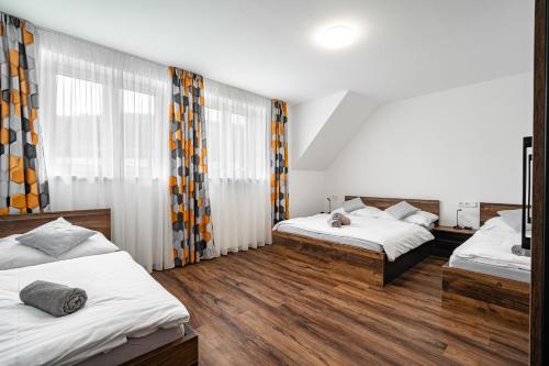 切尔韦纳沃达J-H APARTMÁNY HORSKÝ RESORT BUKOVÁ HORA - 100 m od LANOVKY的一间卧室设有两张床和窗帘,铺有木地板