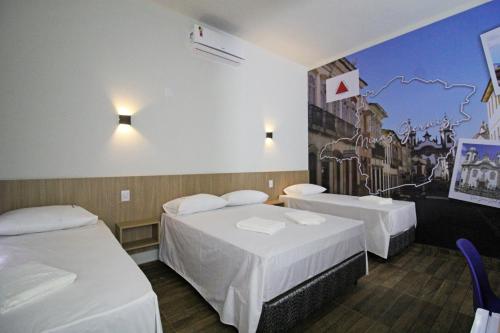 奥林匹亚Pousada das Bandeiras的一间设有两张床的客房,墙上挂着一幅画