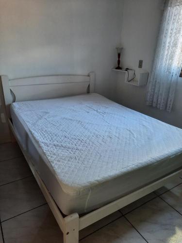 帕苏迪托雷斯Casa de praia的卧室内的一张床铺,配有白色床垫