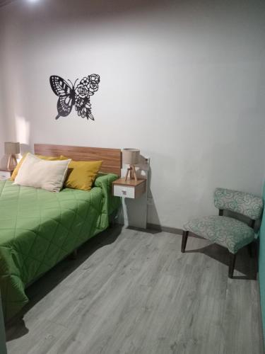 罗卡将军市Casa pura vida的卧室配有一张床,墙上挂着蝴蝶标记