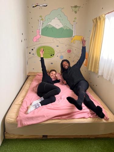 旭川TOTONOU Place的两个女孩手放在床上,双手放在空中