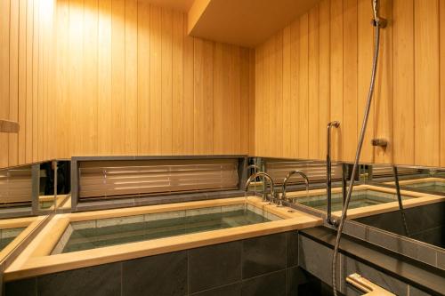 东京ホテルカルタ赤坂的浴室设有浴缸和2个水龙头