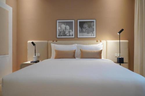 阿布扎比Andalus Al Seef Resort & Spa的一间卧室配有一张带两盏灯的大型白色床。