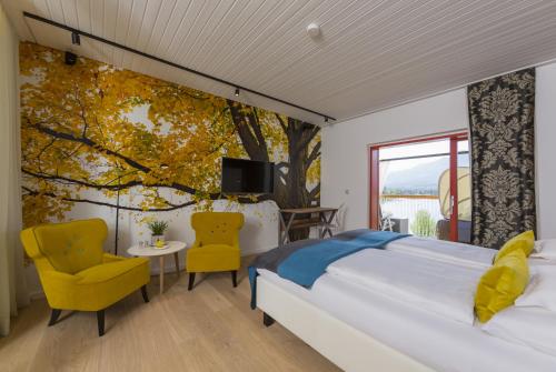 法克湖畔埃格Kleines Hotel Kärnten的一间卧室设有一张大床和一棵树壁画