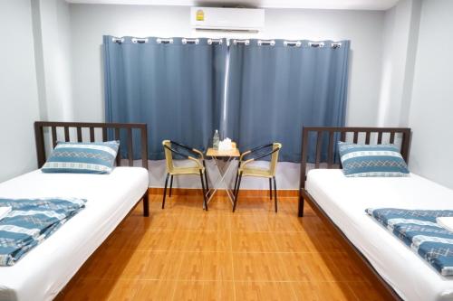 佛丕Chill @ Phetchaburi的一间设有两张床和一张桌子及椅子的房间