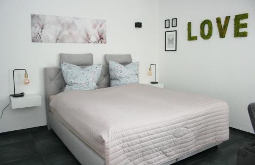 克莱沃Ferienwohnung Die Traumhafte的卧室配有白色床,墙上挂有爱情标志