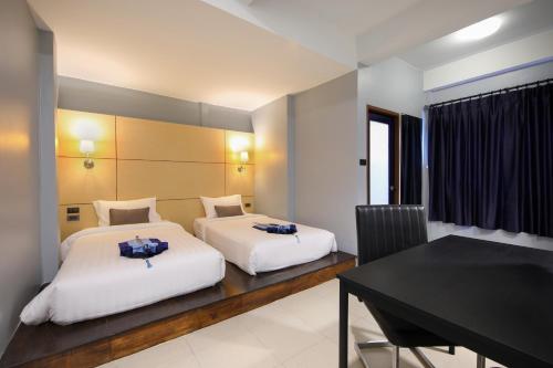 普吉镇Montree Phuket Hotel, SHA Extra Plus的一张桌子和一张书桌的客房内的两张床