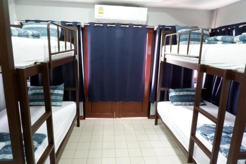 佛丕Chill @ Phetchaburi的带3张双层床和蓝色窗帘的房间