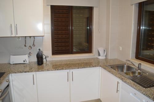 阿尔沃尔Luxury 1-Bedroom Apartment Alvor Duo Village的厨房配有白色橱柜、水槽和窗户。