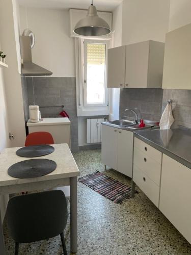 的里雅斯特CASA DENDI的厨房配有白色橱柜、桌子和水槽。