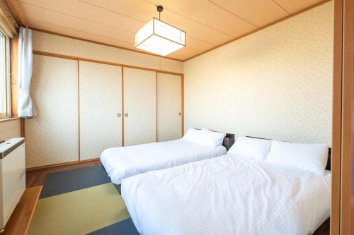 俱知安町Ezo Fujiya Niseko House - Vacation STAY 14767的小客房内的两张床,配有白色床单