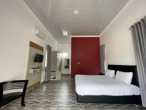 MuntokPONDOK SAHANG COTTAGES的卧室配有白色的床和红色的墙壁