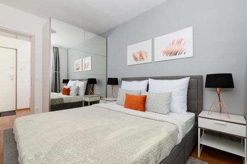 布达佩斯Urban Haven Apartments的卧室配有带橙色枕头的大型白色床