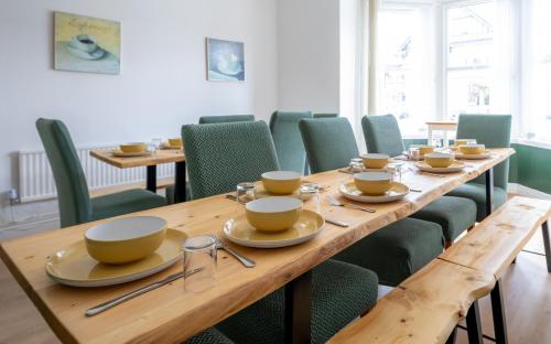 兰迪德诺The Cadnant Holiday House的用餐室配有长木桌子和绿色椅子