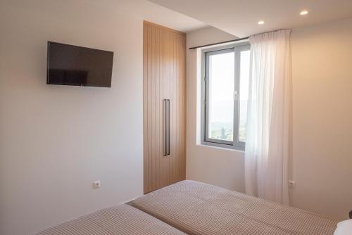 AkritokhórionSunset Luxury Villa的一间卧室设有一张床、一台电视和一个窗口。