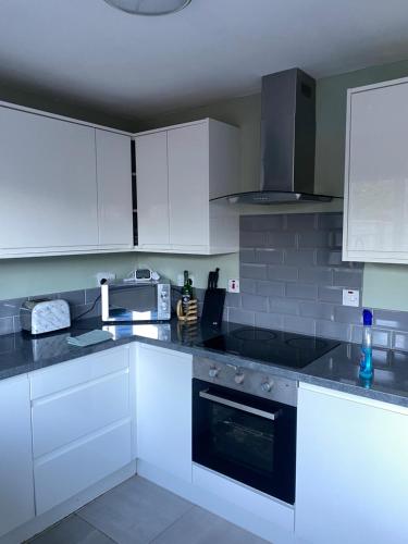 达灵顿Comfy Darlington Home的厨房配有白色橱柜和炉灶烤箱。