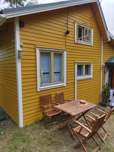 HoutskariMysig Stuga På Houtskär的黄色房子外的桌椅
