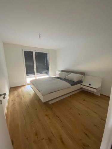特里森贝格Triesenberg的一间铺有木地板的白色卧室,配有一张床