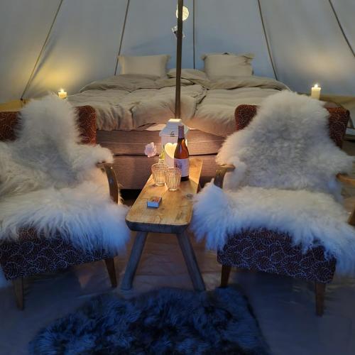 ViksdalenFlatheim Glamping的一间设有两把白色毛绒椅子和一张桌子及一张床的房间