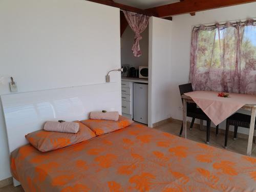 普纳奥亚Bungalow Miwa的一间卧室配有一张床铺和一张桌子,还设有一间厨房