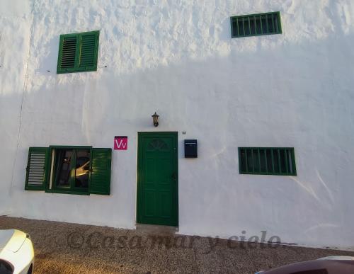 普拉亚布兰卡Casa mar y cielo的白色的建筑,设有绿色的门和窗户