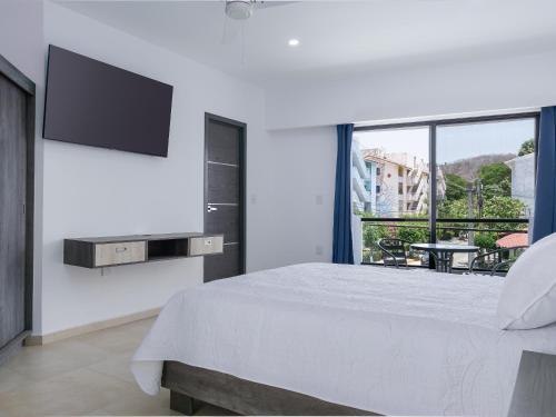 圣克鲁斯华特库Casa Xtao Hotel的白色卧室设有一张大床和一台平面电视。