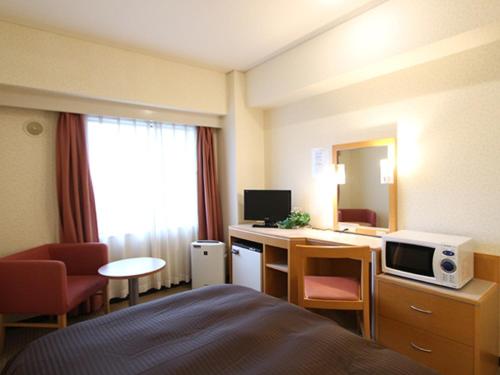 横滨HOTEL LiVEMAX BUDGET Yokohama Kannai的酒店客房配有一张床和一张带微波炉的书桌