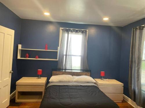 梅里登fashionably cozy place的一间卧室设有蓝色的墙壁和一张带两盏灯的床。