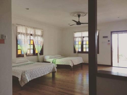 Kampong Pasir PutehMILLBROOK HOUSE TERENGGANU的客房设有两张床和吊扇。
