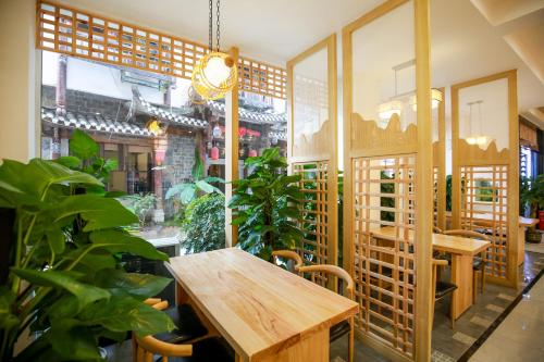 张家界武陵山水客栈Wuling Shanshui Hotel的一间设有木桌和一些植物的餐厅