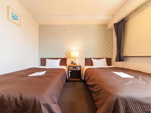 相模原市HOTEL LiVEMAX BUDGET Sagamihara的酒店客房,设有两张床和一盏灯