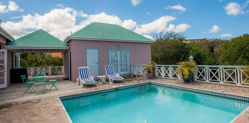 CliftonsMandevilla Nevis的一个带两把椅子的游泳池以及一座房子