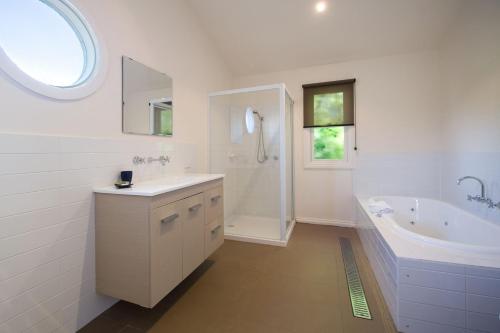 戴尔斯福特海滩小屋度假屋的白色的浴室设有水槽、浴缸和淋浴。