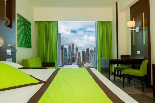巴拿马城Riu Plaza Panamá的一间卧室配有一张绿色的床、一张桌子和一个窗户。
