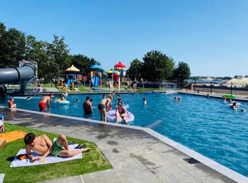 LathumFerienhaus LuxChalet VAJU IJsselView direkt am Fluss See Pool Park的一群人在水上公园的游泳池里