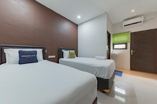 TumbangrunganUrbanview Hotel Yoga Palangkaraya by RedDoorz的一间酒店客房,设有两张床和一扇门