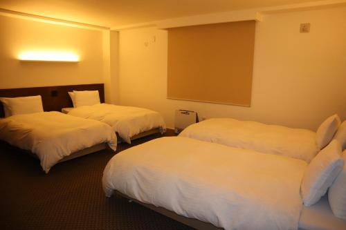 饭山市Aki's Apartments Madarao的酒店客房,配有3张带白色床单的床