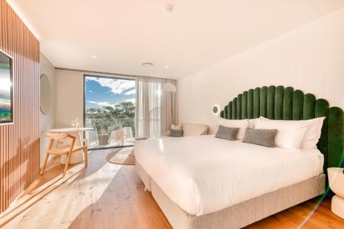 佩里吉安比奇Essence Boutique Hotel的一间卧室配有一张白色大床和绿色床头板