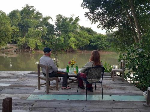 Sam Chukสามชุกบ้านสวน的坐在河边桌子旁的男人和女人