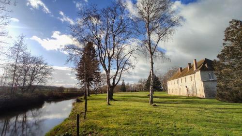 Les BauxAbbaye Saint Gilbert的河岸边的一座有树木的建筑