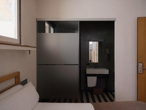 圣塞瓦斯蒂安Guest House Ibaia Et Arramak的一间卧室设有一扇门,可通往带水槽的浴室
