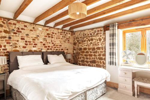 PentneyThe Gig House - relaxing countryside spa break的一间卧室设有一张床和砖墙