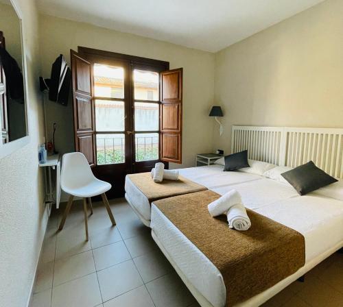 阿尔卡拉德荷那利斯米格尔·德·塞万提斯酒店的一间卧室配有两张床、一张桌子和一把椅子