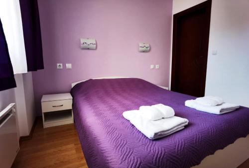潘波洛沃Апартамент 204 Студенец的紫色的床,上面有两条毛巾